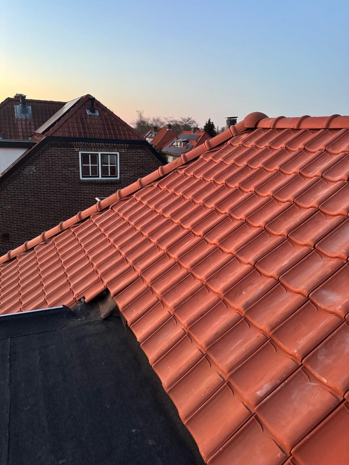 Close-up van rode dakpannen met nieuw geplaatste nokvorsten.