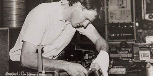 Oude zwart-witfoto van een dakdekker die een pannendak legt.